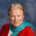 Lee Lawrence Lee Lawrence - a smiling caucasian woman's head shot, with hair pulled back and a turquoise scarf that matches her eyes. Red jacket. White shirt.
