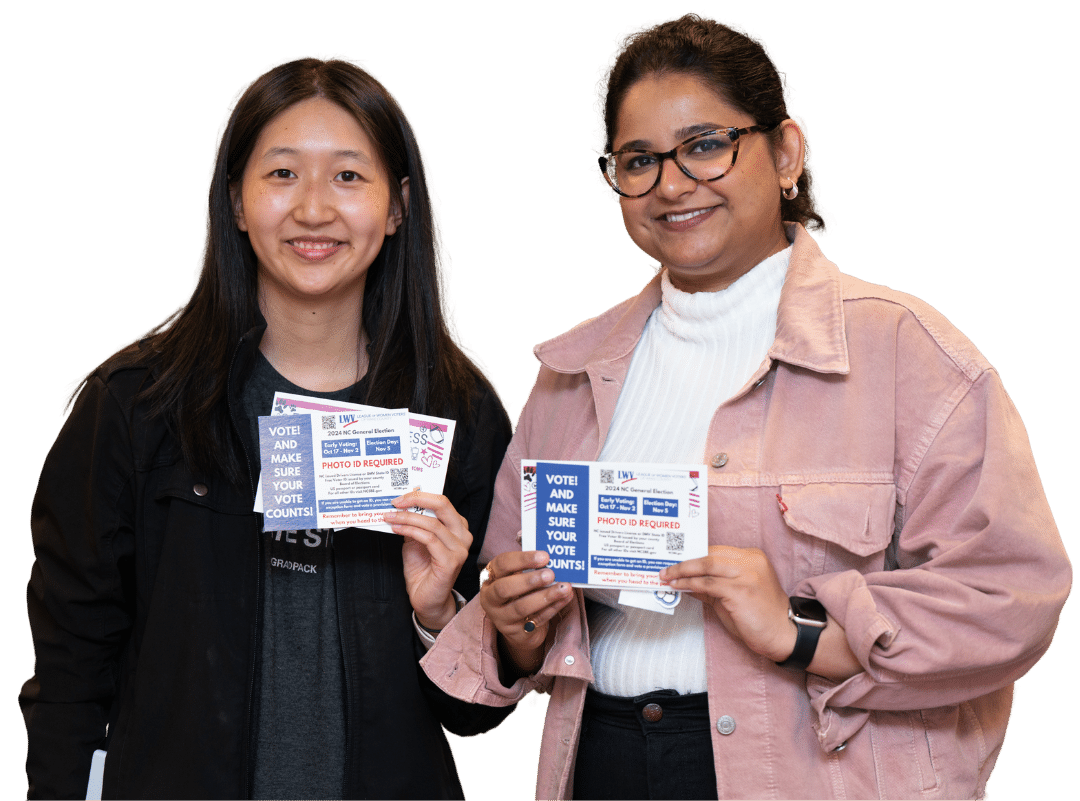 Two women stand together holding pamphlets